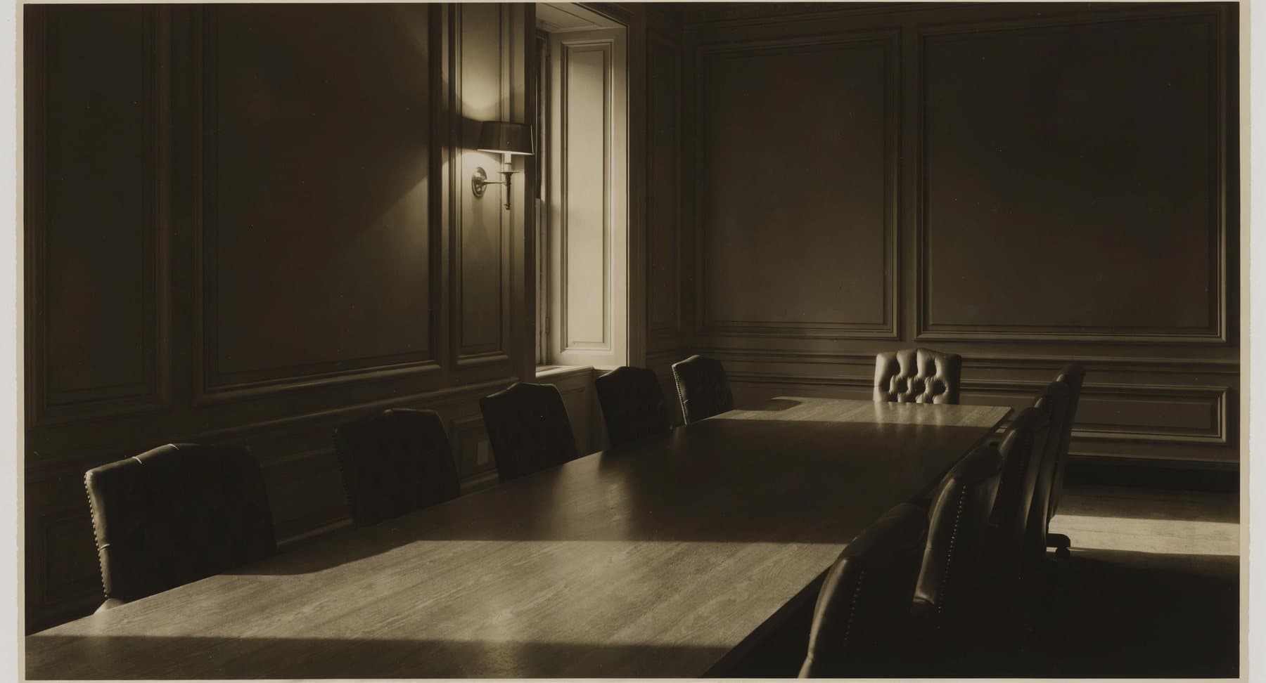 An empty private boardroom with a long walnut table